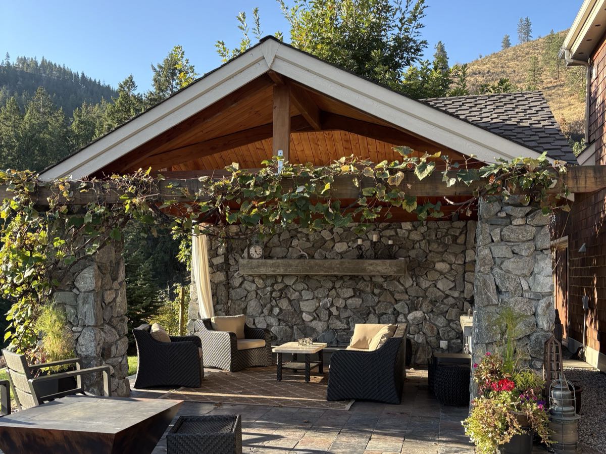 Covered outdoor living room with granite stone columns and slate patio