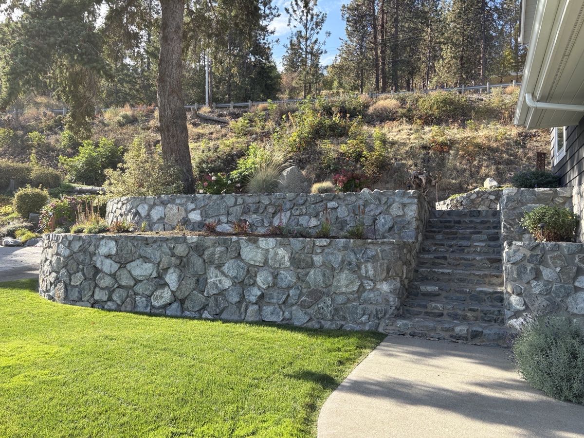 Tiered granite retaining wall with stone steps and planted beds