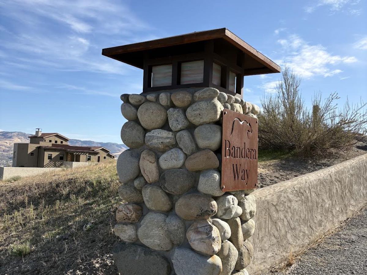 River-rock entry pillar with timber cap, lantern and carved sign