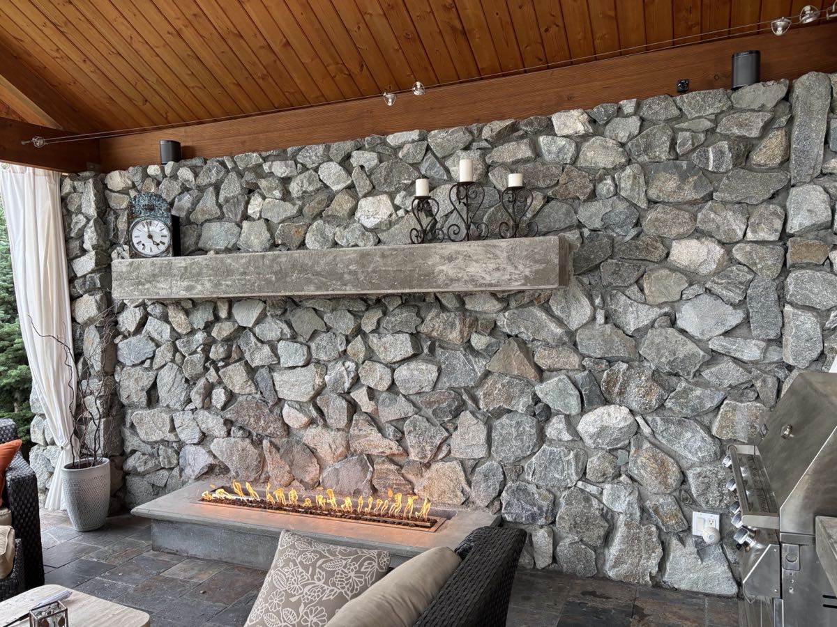 Hand-laid granite fireplace wall with linear gas fire and concrete mantel